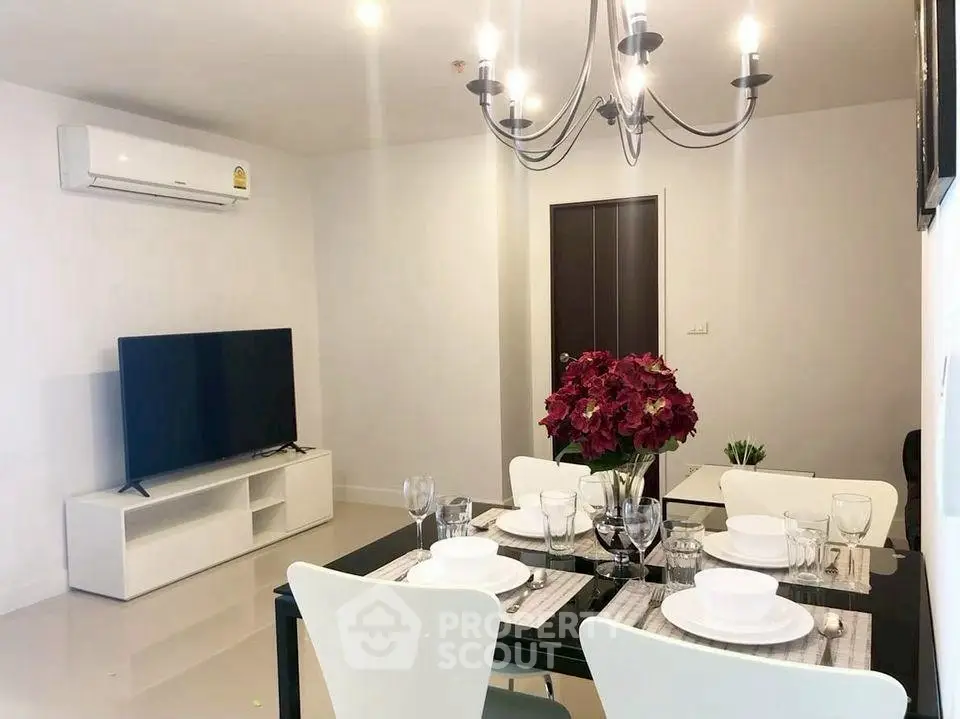 Modern dining area with elegant chandelier and sleek TV setup