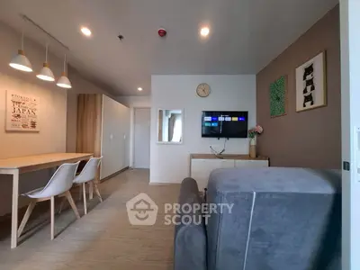Modern living room with stylish decor and wall-mounted TV, featuring a cozy seating area and dining space.