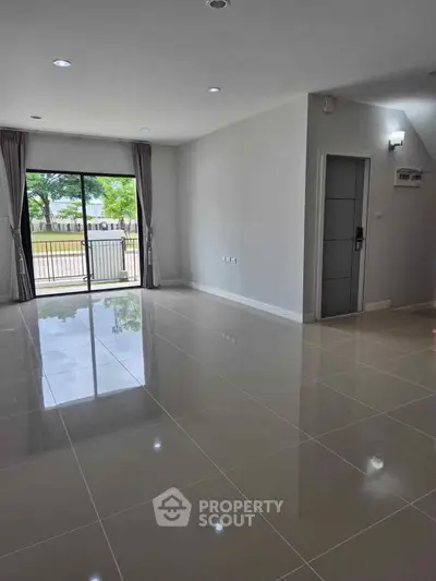 Spacious modern living room with large windows and glossy tiled floors.