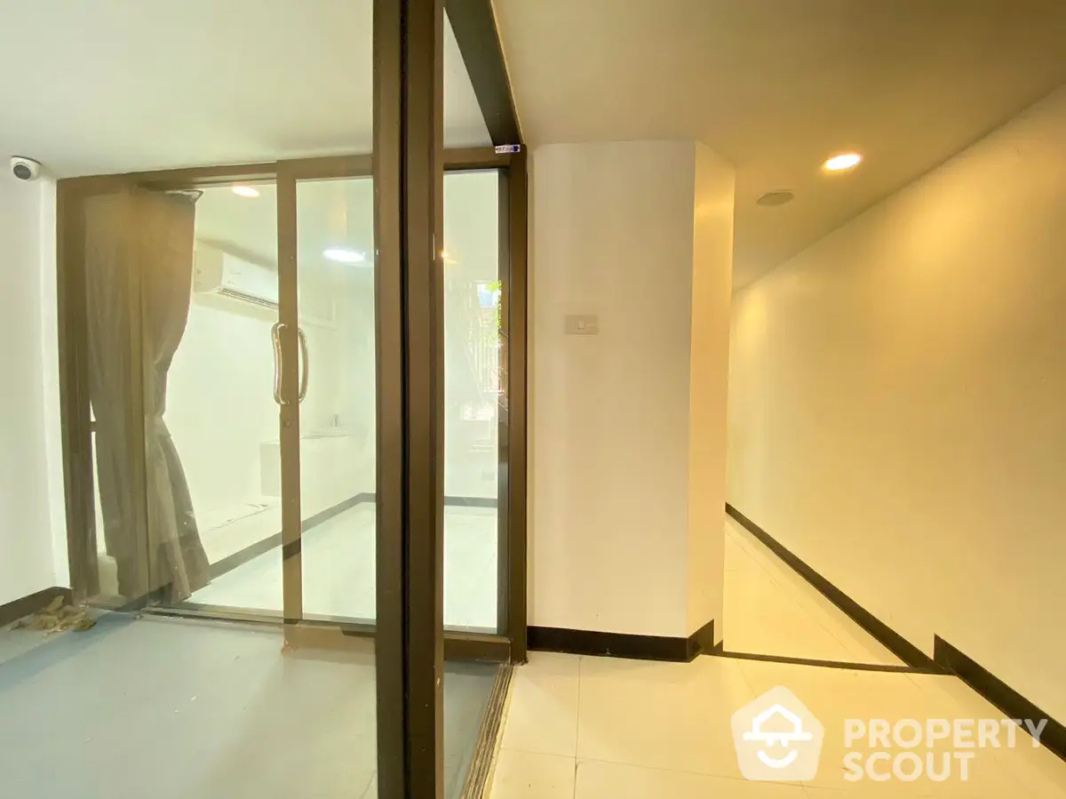 Bright and airy corner unit with sleek glass doors leading to a spacious living area, featuring modern lighting and a clean, minimalist design.