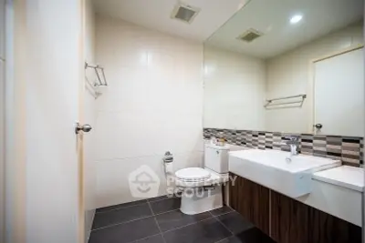 Modern bathroom with sleek design, featuring a stylish sink and contemporary tiling.