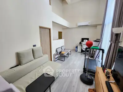 Modern living room with high ceiling, treadmill, and stylish furniture in a bright, airy space.