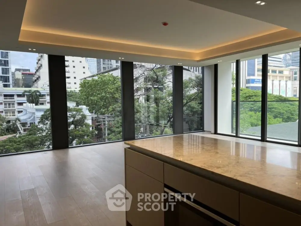 Spacious modern living room with large windows offering a stunning city view, featuring sleek wooden flooring and elegant lighting.