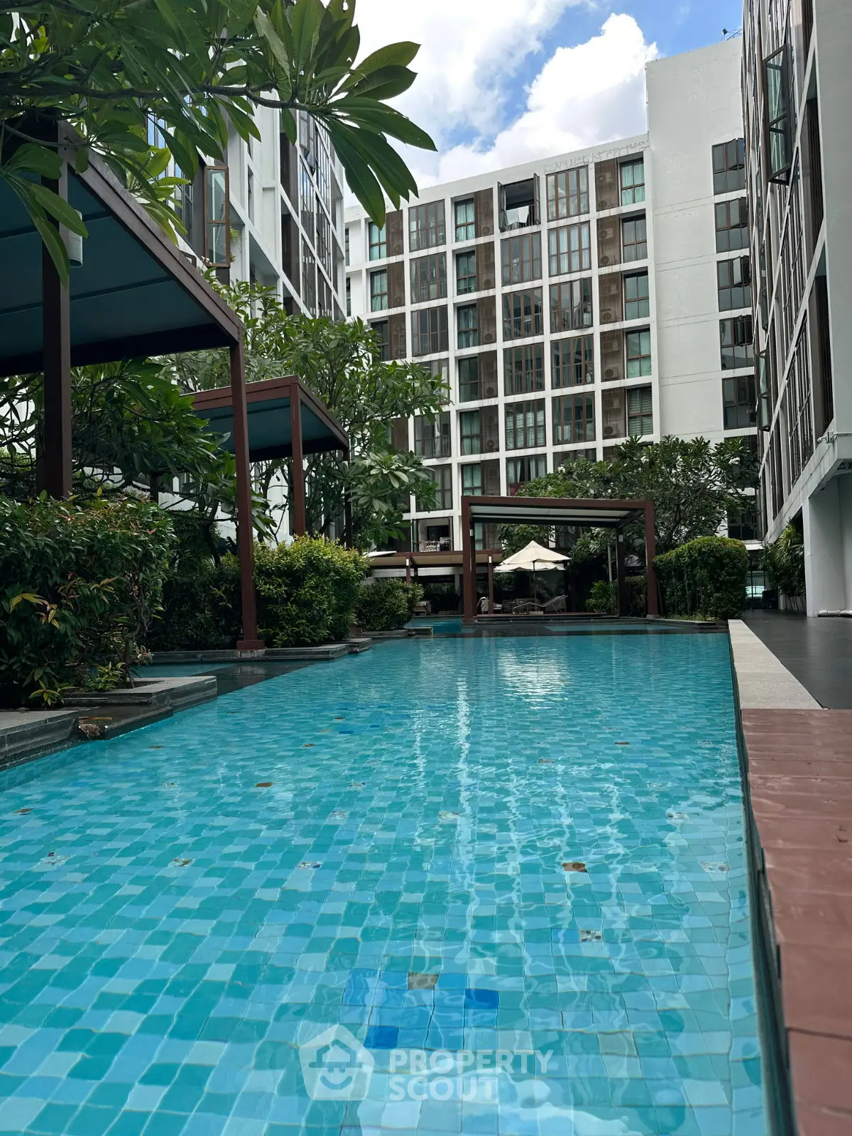 Luxurious condominium with a stunning outdoor pool and lush greenery, perfect for relaxation and leisure.