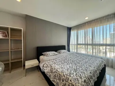 Spacious bedroom with large windows offering city views, modern decor, and ample natural light.