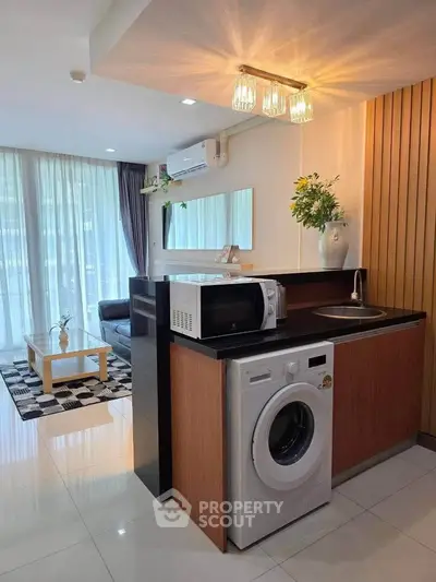Modern living room with washing machine and microwave in stylish open layout.