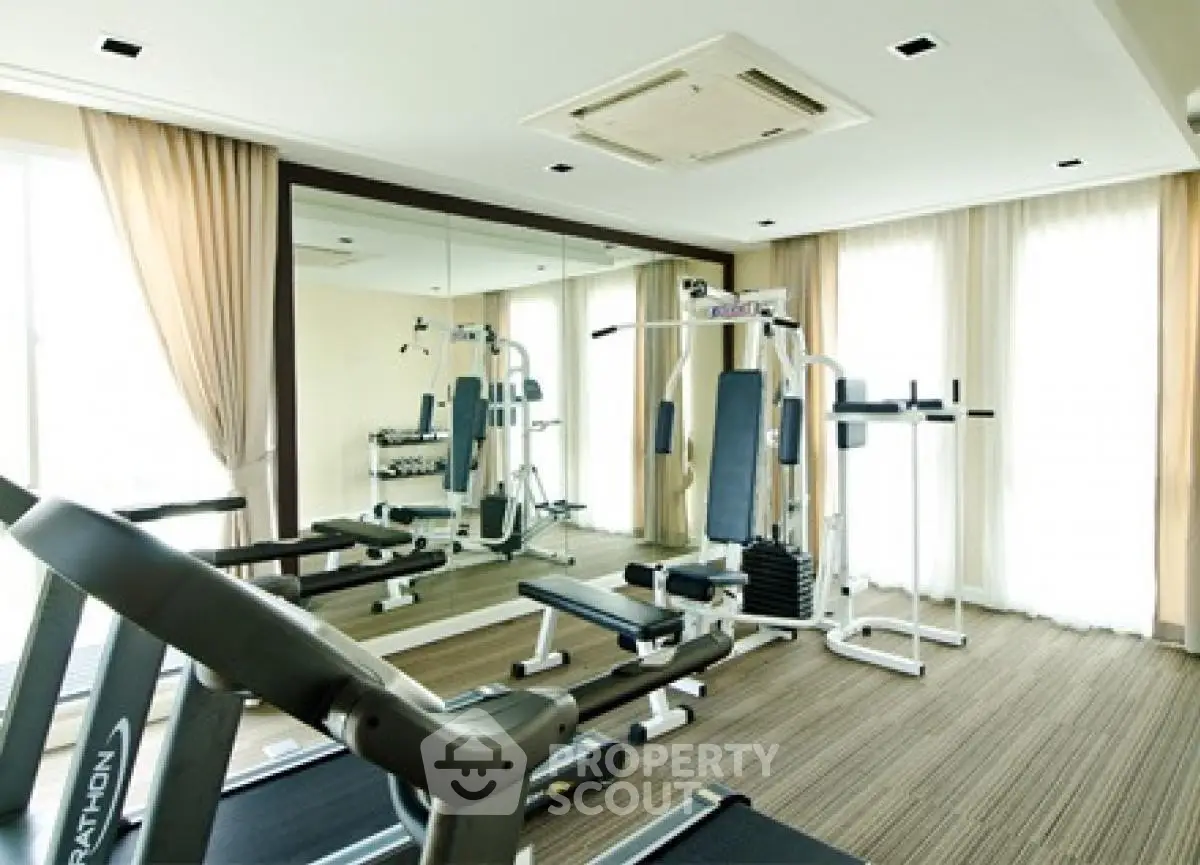 Modern gym with state-of-the-art equipment and mirrored walls in a luxury apartment building.