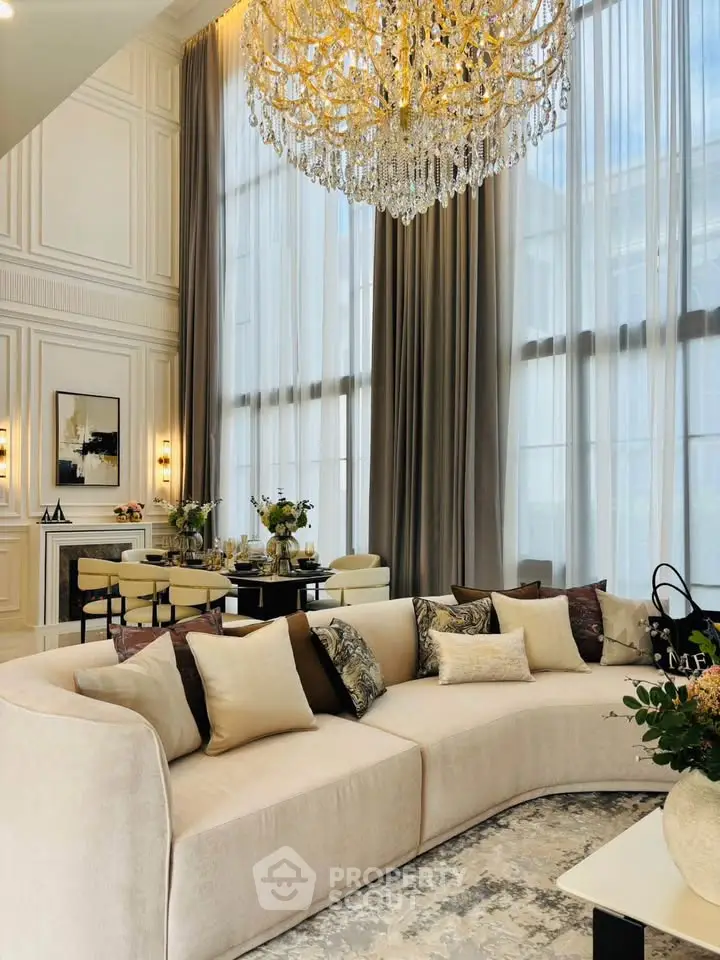 Luxurious living room with high ceilings, elegant chandelier, and plush seating in a sophisticated setting.