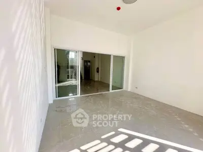 Spacious empty room with glossy tiled floor and large sliding glass doors.