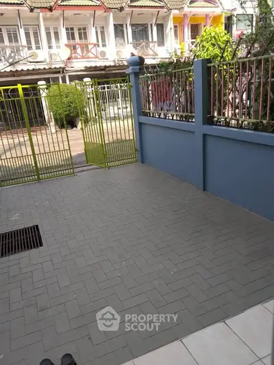 Charming townhouse exterior with gated entrance and paved courtyard.