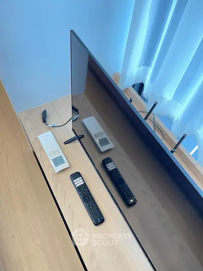 Modern living room with sleek TV setup and remote controls on wooden console.