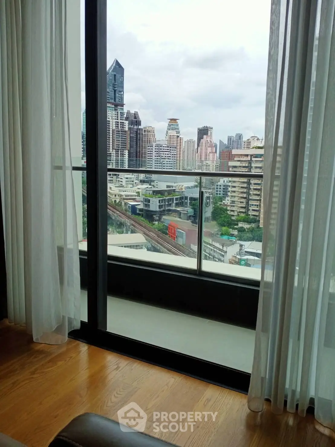 Stunning city view from modern apartment balcony with floor-to-ceiling windows.