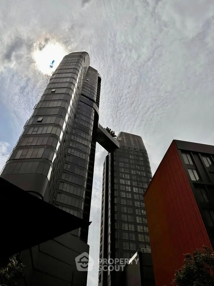 Stunning modern skyscrapers with unique architectural design and sky bridge under a dramatic cloudy sky.