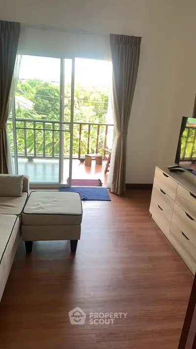 Bright living room with balcony view and modern furniture, perfect for relaxation.