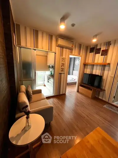 Charming living room with modern decor and cozy ambiance, featuring a compact kitchen and stylish furnishings.