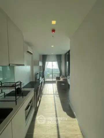 Modern apartment with open kitchen and bright living area, featuring large windows and stylish decor.