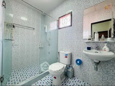 Modern bathroom with glass shower and mosaic tiles, featuring sleek fixtures and bright lighting.