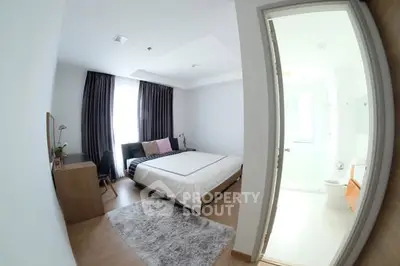 Spacious bedroom with modern decor and ensuite bathroom, featuring large windows and elegant furnishings.