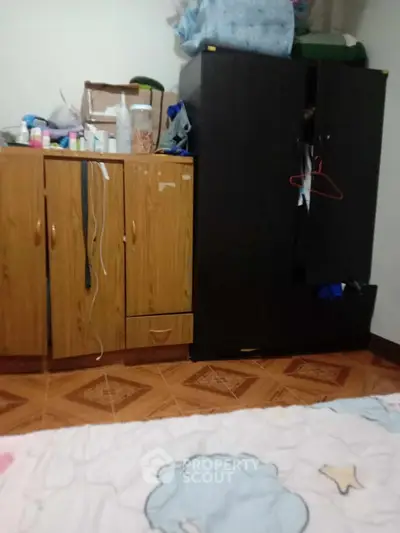 Cozy bedroom with wooden cabinets and tiled flooring, perfect for compact living spaces.