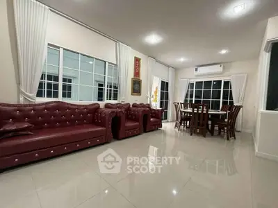Spacious living room with elegant red leather sofas and dining area, featuring large windows and glossy tiled floors.