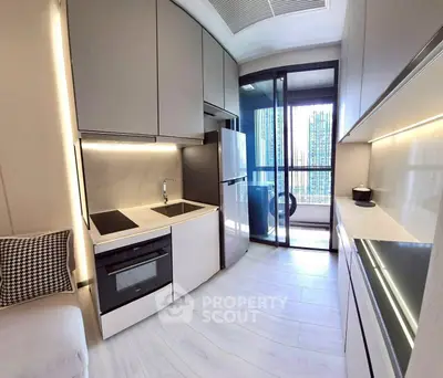 Modern kitchen with sleek cabinetry and balcony view in a stylish apartment.