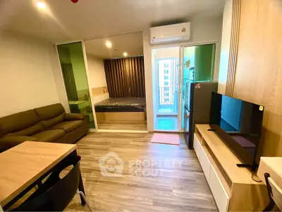 Modern apartment interior with open living room and bedroom, featuring sleek furniture and wooden flooring.