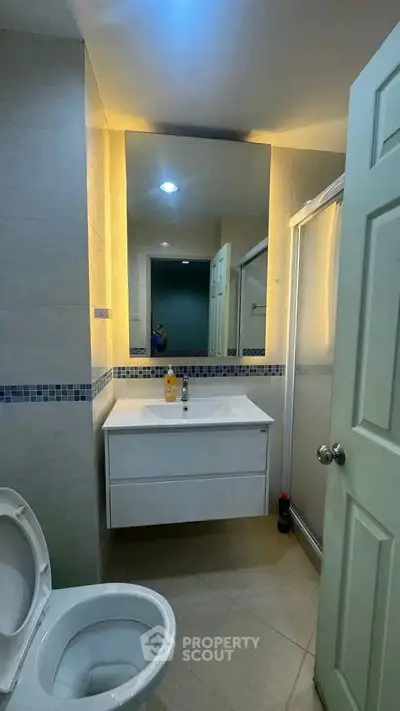 Modern bathroom with sleek vanity and shower enclosure, featuring elegant lighting and contemporary design.