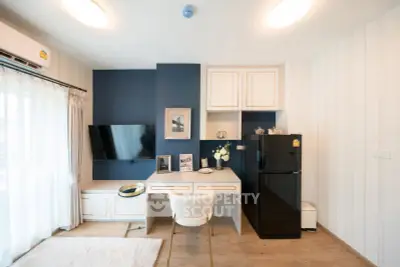 Modern living room with stylish decor, featuring a sleek black fridge and elegant desk setup.
