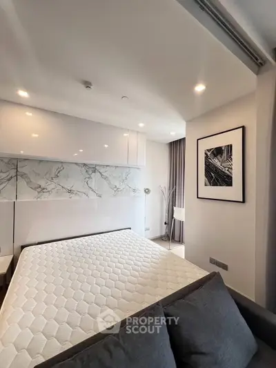 Modern bedroom with stylish decor and natural light, featuring a comfortable bed and elegant wall art.