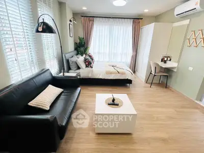 Modern studio apartment with stylish decor, featuring a cozy bed, sleek sofa, and ample natural light.