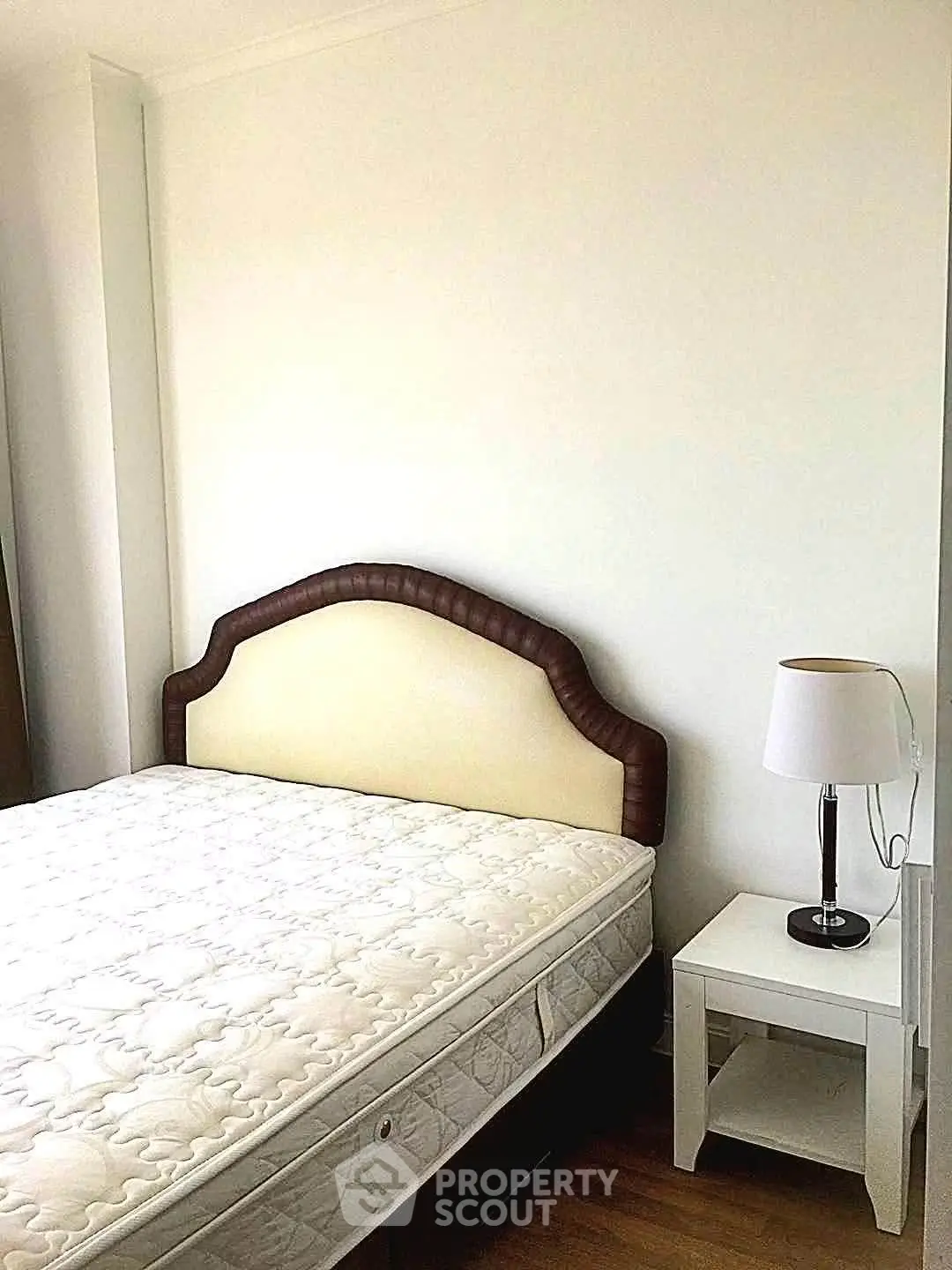Cozy bedroom with elegant headboard and bedside lamp, perfect for restful nights.