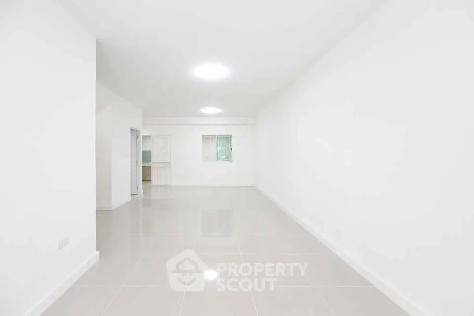 Spacious minimalist living room with glossy tiled floors and bright lighting, perfect for modern living.
