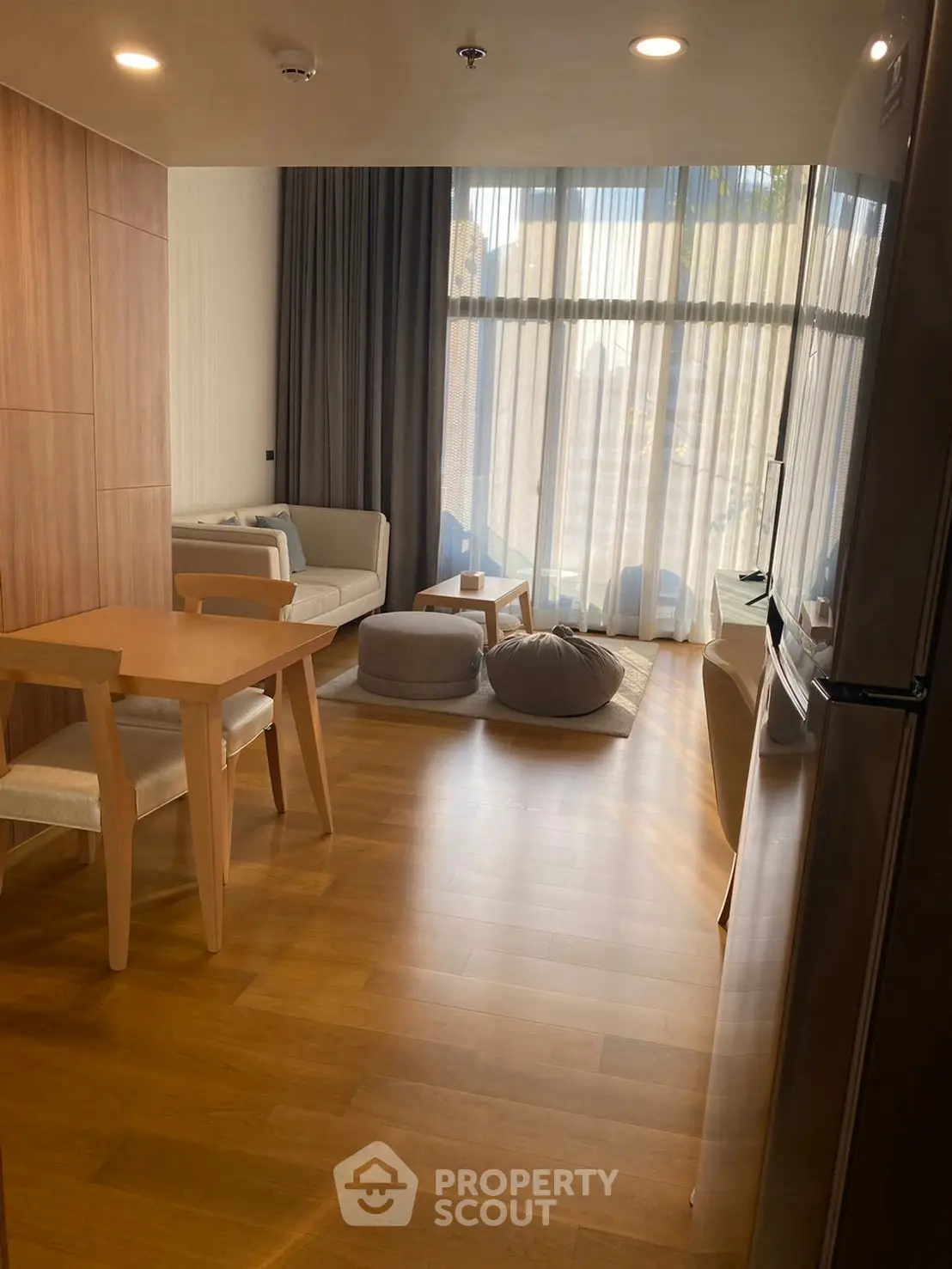 Modern living room with wooden flooring and large windows for natural light