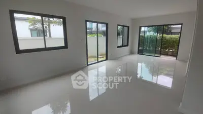 Spacious modern living room with large windows and glossy floors in a contemporary home.