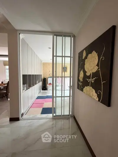 Spacious hallway leading to a stylish living area with modern decor and elegant wall art.