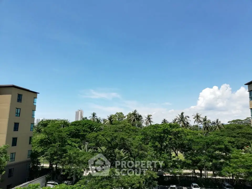 Stunning view from apartment balcony overlooking lush greenery and city skyline.