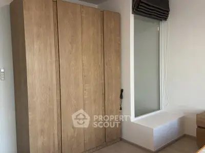 Modern bedroom with sleek wooden wardrobe and large window for natural light.