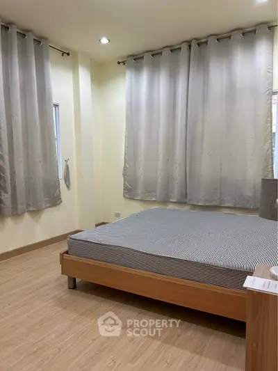 Spacious bedroom with modern design and ample natural light, featuring elegant curtains and a comfortable bed.