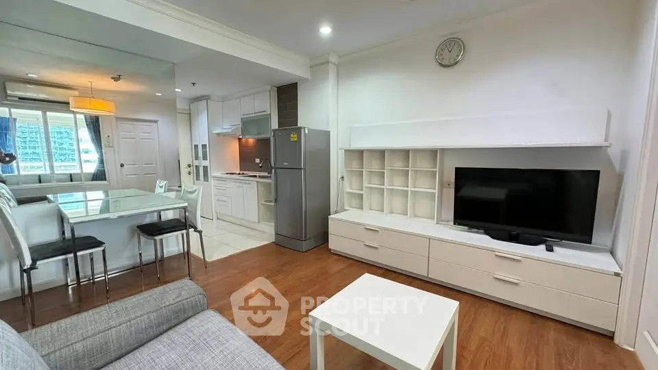 Modern open-plan living room with kitchen and dining area, featuring sleek furniture and natural light.