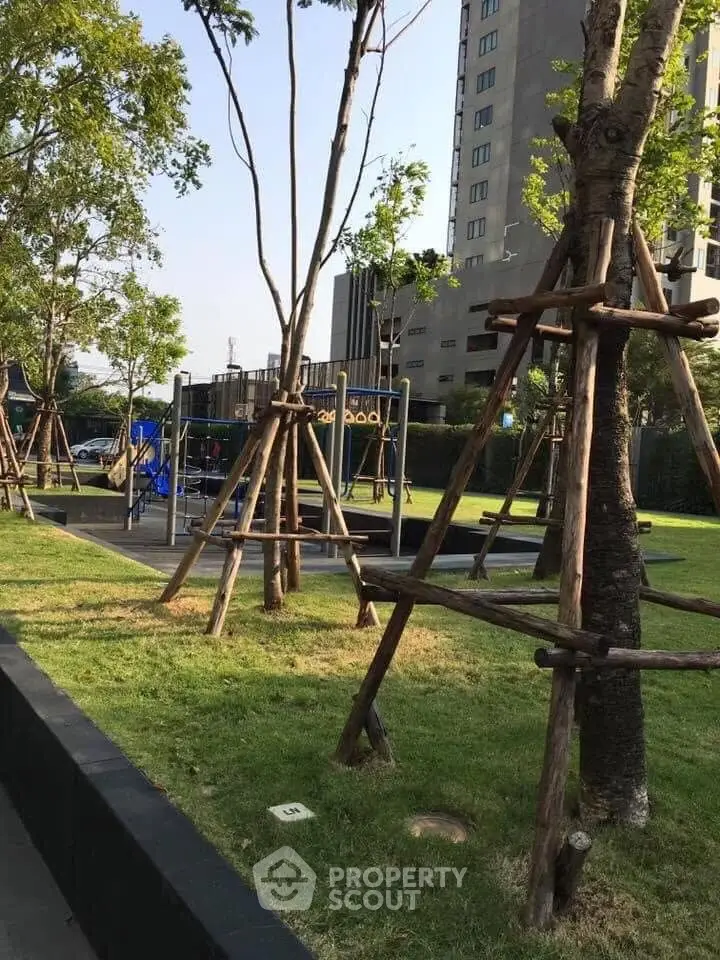 Modern residential building with lush green garden and playground area.