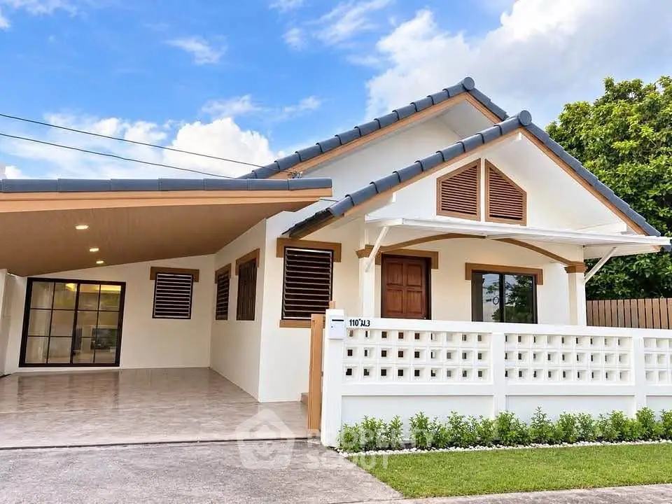 Charming single-story home with modern design and spacious carport, featuring a white facade and lush greenery.