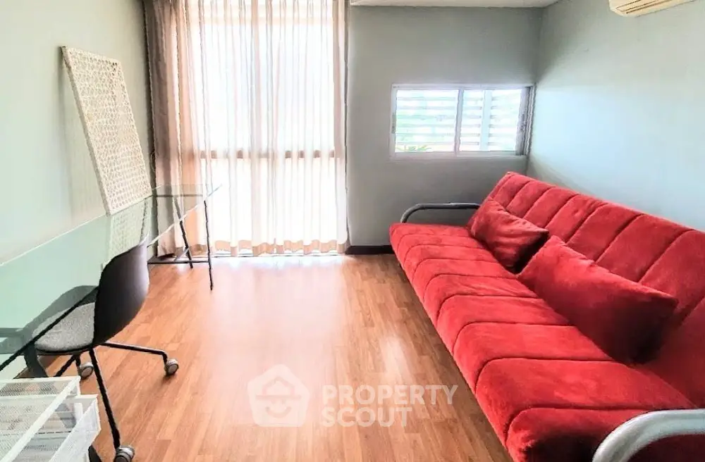 Modern living room with red sofa and glass desk, perfect for a cozy home office setup.