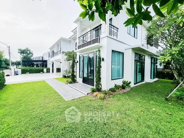 Modern white two-story house with lush green lawn and large windows, showcasing contemporary architecture.