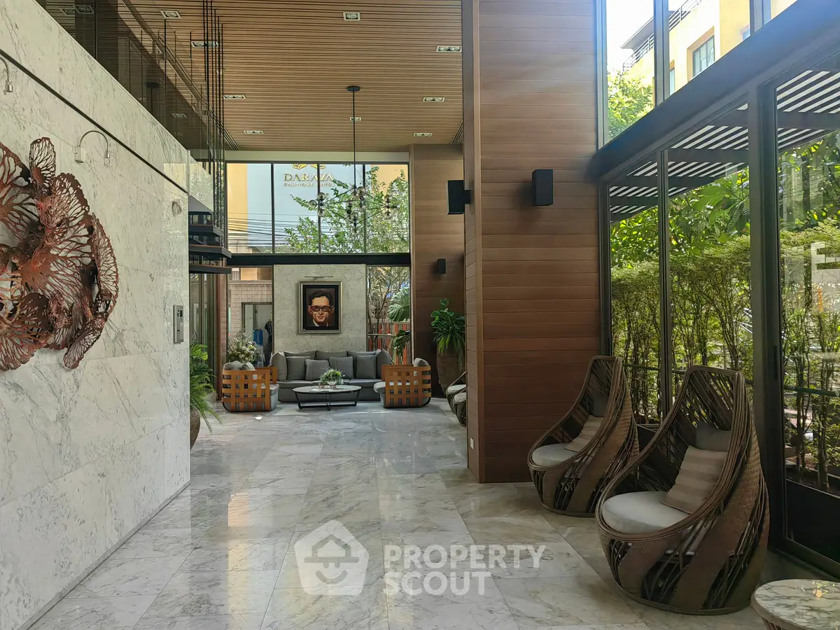 Luxurious modern lobby with elegant seating and art decor, featuring floor-to-ceiling windows and lush greenery.