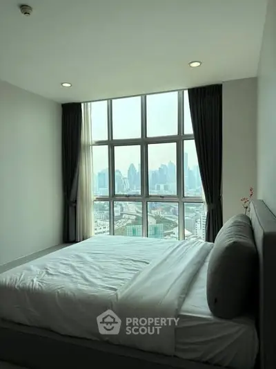 Modern bedroom with large windows offering stunning city view