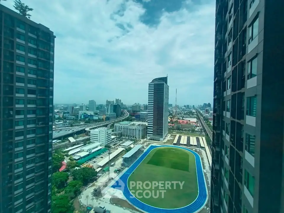 Stunning cityscape view from high-rise building with track field and skyline