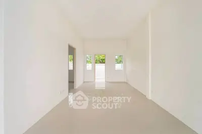 Spacious empty room with glossy tiled floor and large windows offering natural light.
