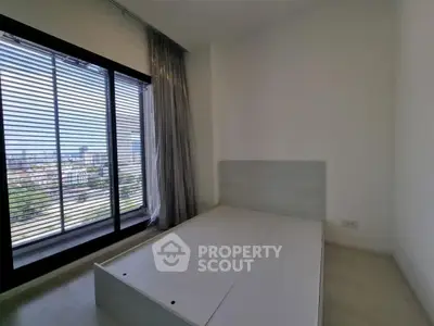 Spacious bedroom with large window offering stunning city view