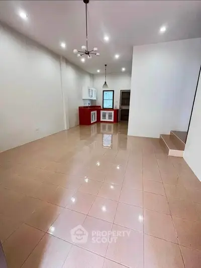 Spacious open-plan kitchen and living area with modern lighting and tiled flooring.