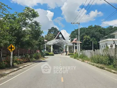 Charming residential entrance with lush greenery and clear blue skies.